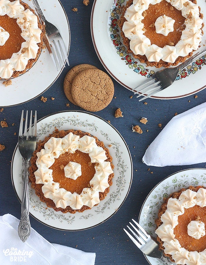 overhead shot of four mini sweet potato tarts on different plates against a blue background