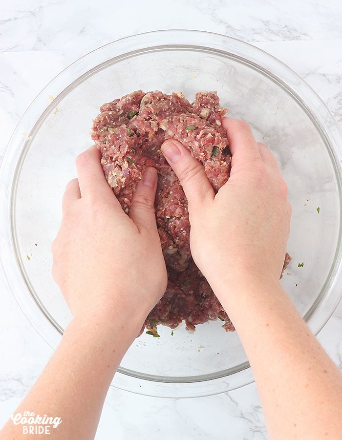 pair of hands mixing the meatballs together