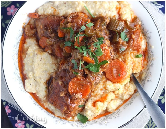 Fork tender country style slow cooker pork ribs are simmered with vegetables and served over a bed of creamy Parmesan corn grits.