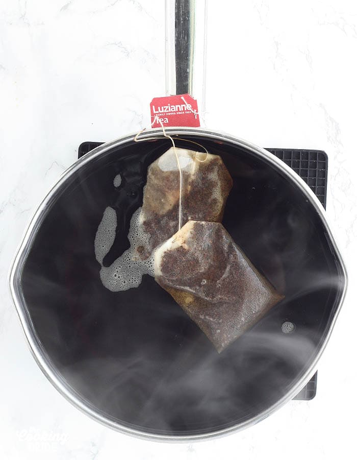 tea bags steeping in a stainless steel pot
