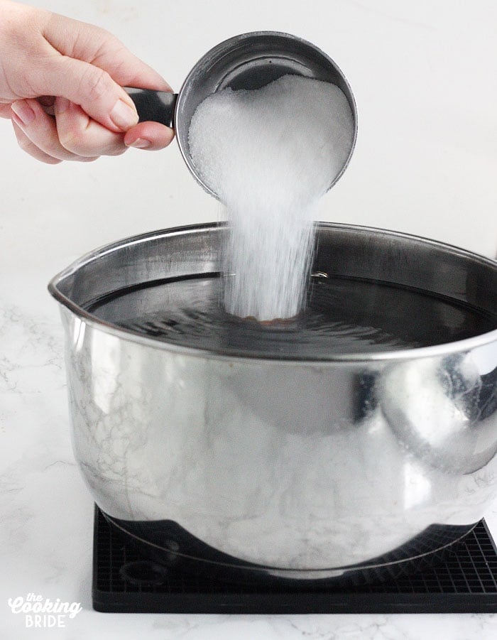 pouring sugar into the pan of steeped tea