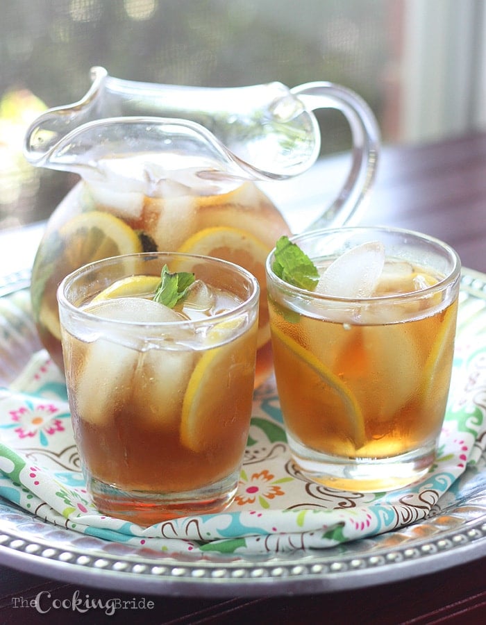 pitcher of sweet tea and two glasses on a pewter serving tray infront of a window