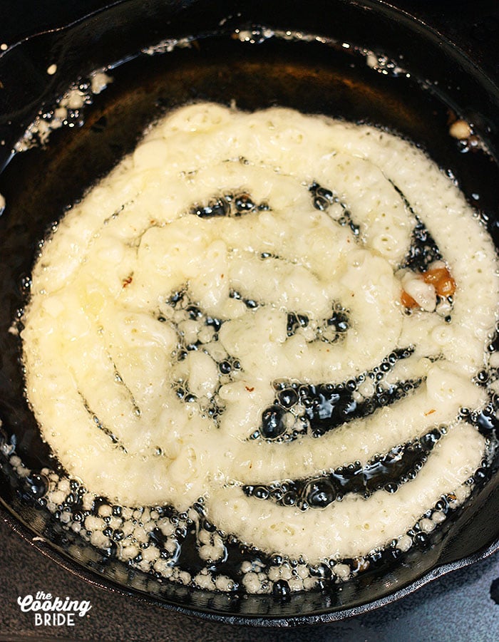 batter frying in hot oil in a cast iron skillet