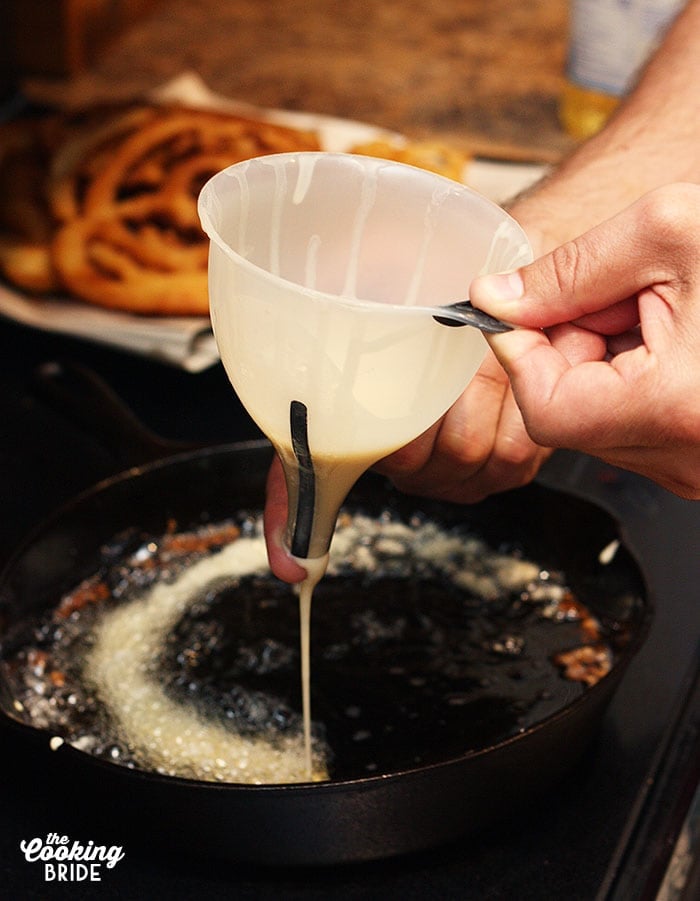 pouring the batter through a funnel into hot oil