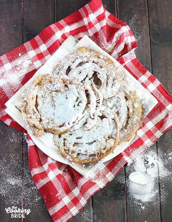 funnel cakes covered in powdered sugar on a red napkin