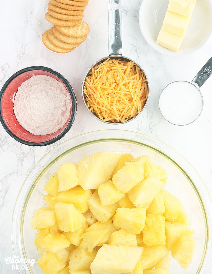 ingredients for pineapple casserole including pineapple chunks, flour, shredded cheese, Ritz crackers, butter and sugar