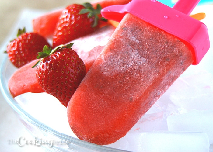 strawberry Frozen Popsicles and fresh strawberries laying on a bowl of ice