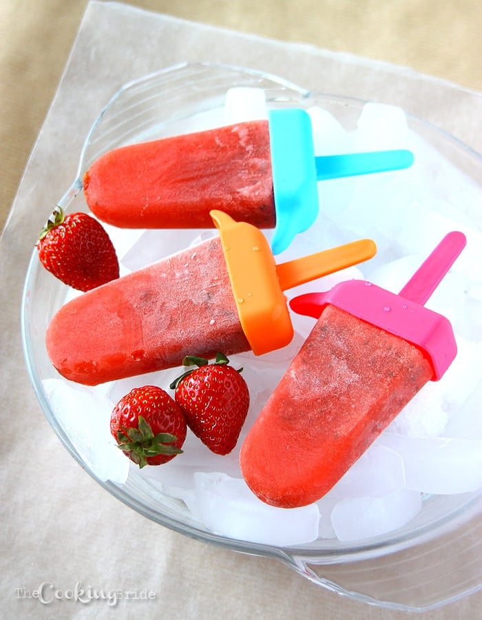 strawberry Frozen Popsicles and fresh strawberries laying on a bowl of ice