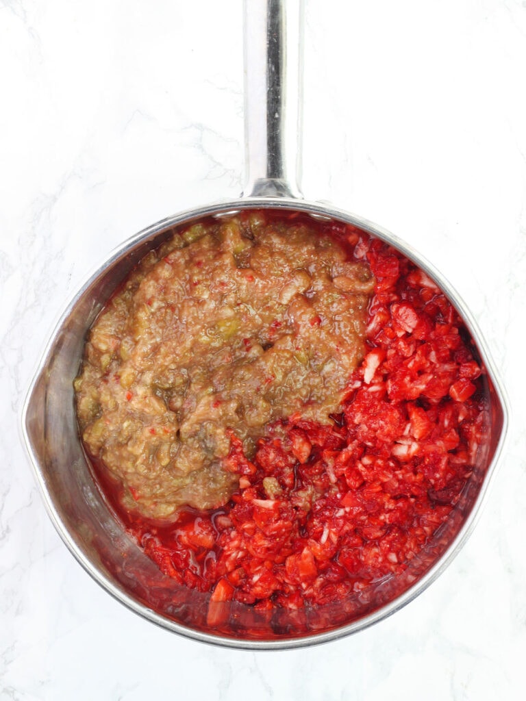 Chopped strawberries and figs unmixed in a stainless steel saucepan.