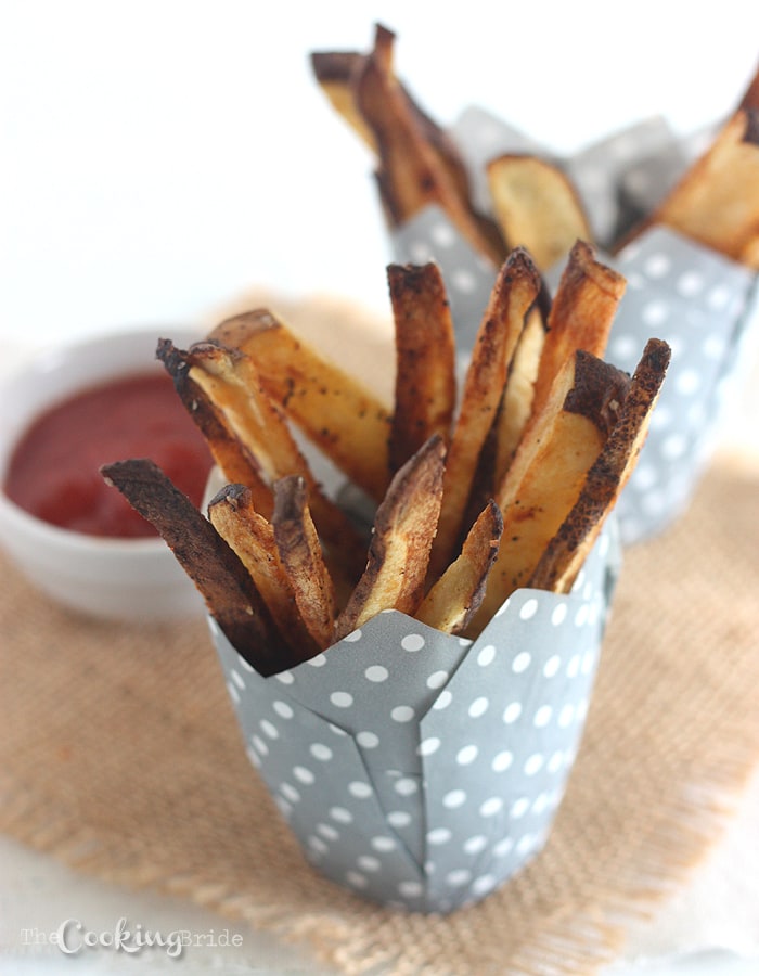 french fries in a gray paper cup with ketchup on the side.