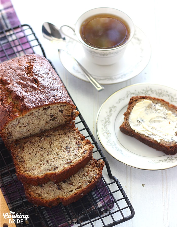 Homemade Banana Bread on a cooling rack with a cup of tea in the background.