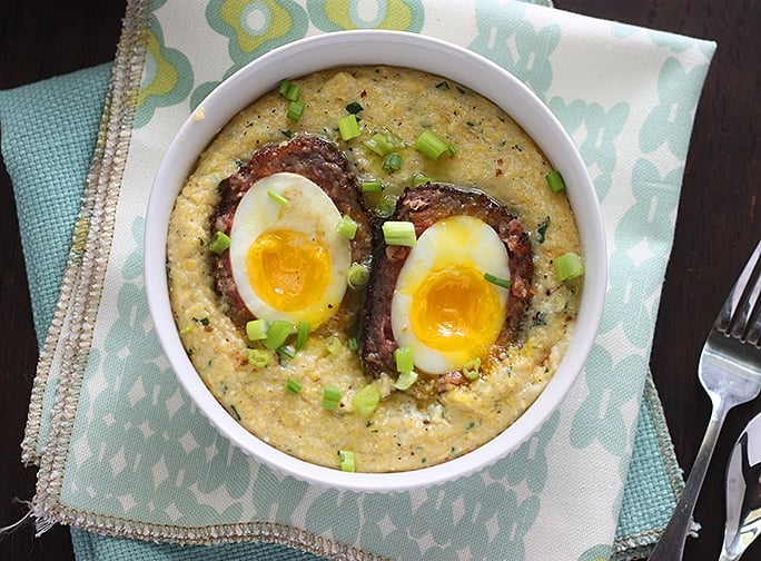 Easy to make scotch egg recipe is the perfect brunch! Soft boiled eggs are wrapped in sausage, dredged in Panko breadcrumbs, the fried until golden brown. Served over creamy, buttered herb corn grits.
