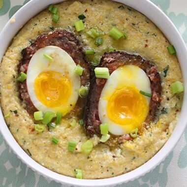 Easy to make scotch egg recipe is the perfect brunch! Soft boiled eggs are wrapped in sausage, dredged in Panko breadcrumbs, the fried until golden brown. Served over creamy, buttered herb corn grits.