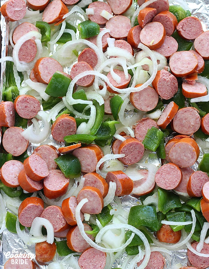 chopped sausage and veggies arranged on a foil lined baking sheet