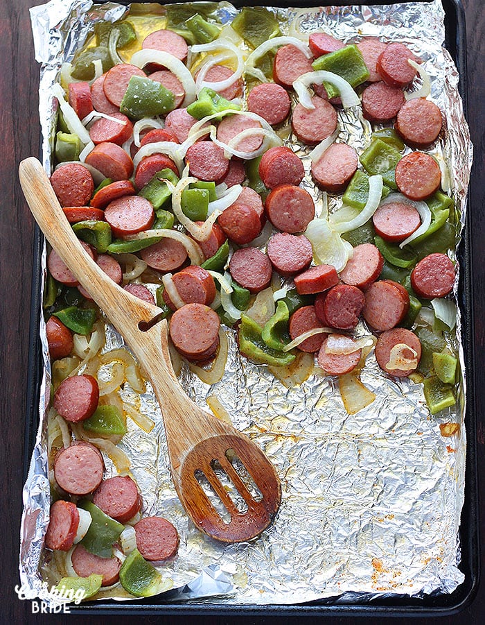 roasted sausage and veggies being served with a wooden spoon
