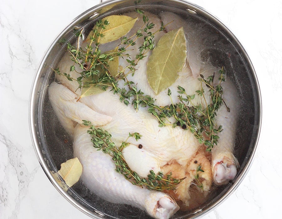 Brining Basics - whole chicken soaking in salt water in a metal stock pot