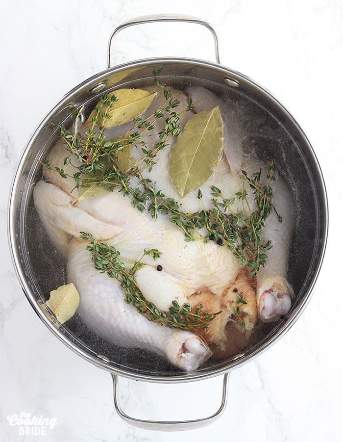 Brining Basics - whole chicken soaking in salt water in a metal stock pot