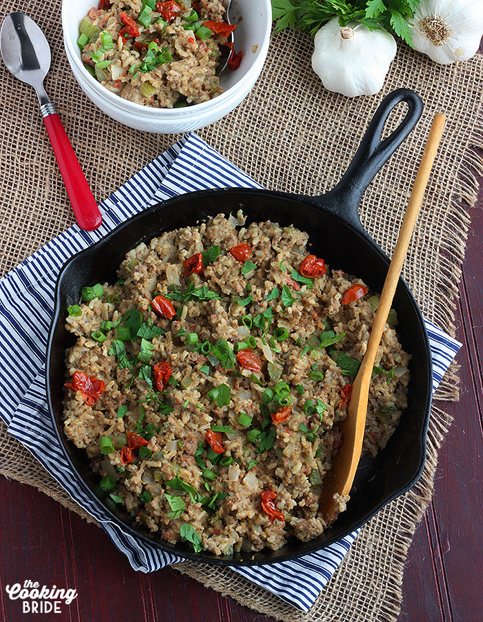 overhead shot of dirty rice in a cast iron skillet with a wooden spoon