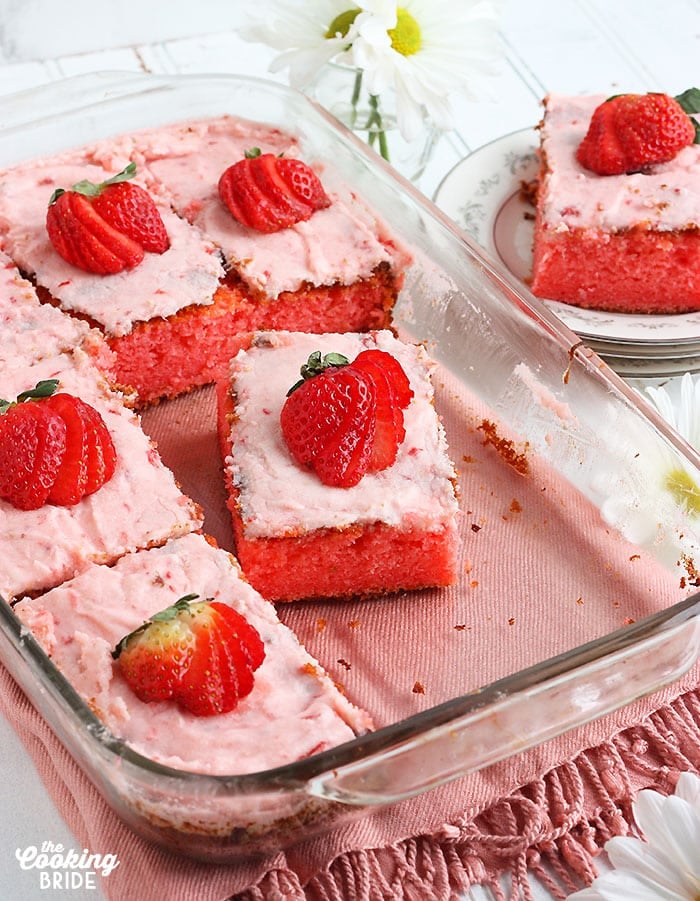 cut slices of strawberry sheet cake in a glass baking dish
