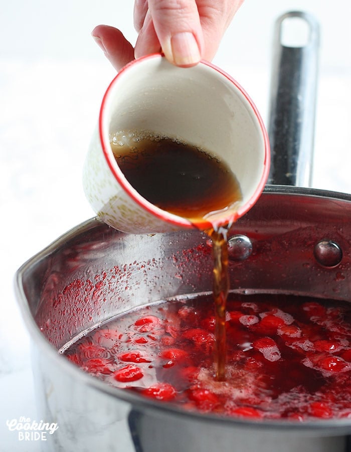 hand pouring soda into a saucepan of warm strawberry gelatin