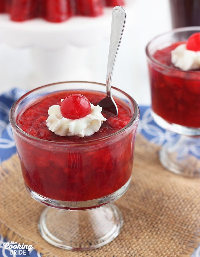 close of up Coca Cola Jello Fruit in a glass bowl topped with whipped cream