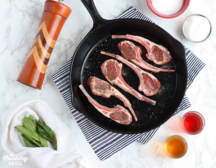 uncooked lamb chops in a skillet surrounded by recipes ingredients