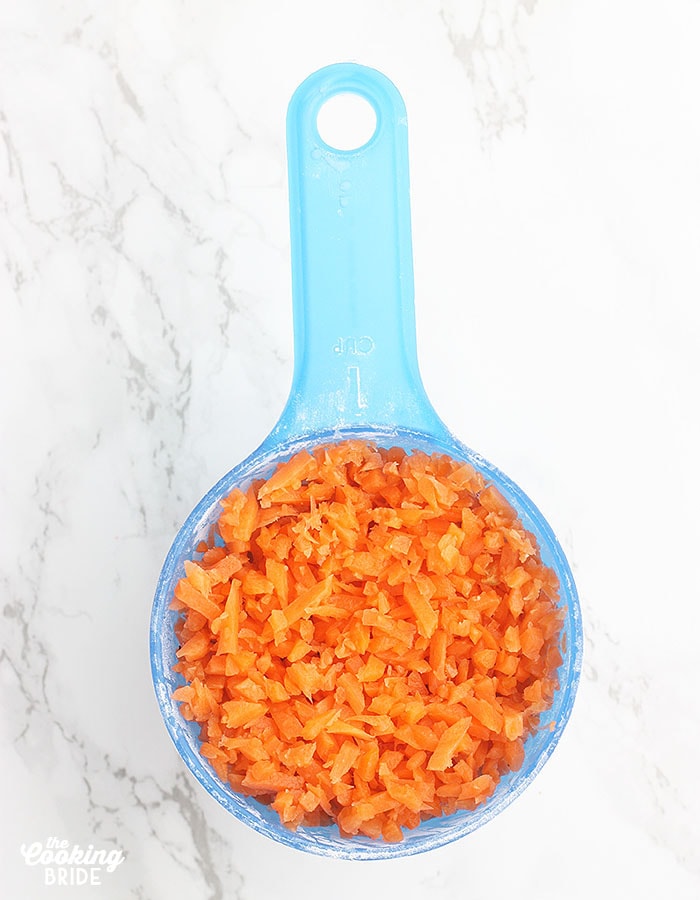 blue measuring cup with shredded carrots