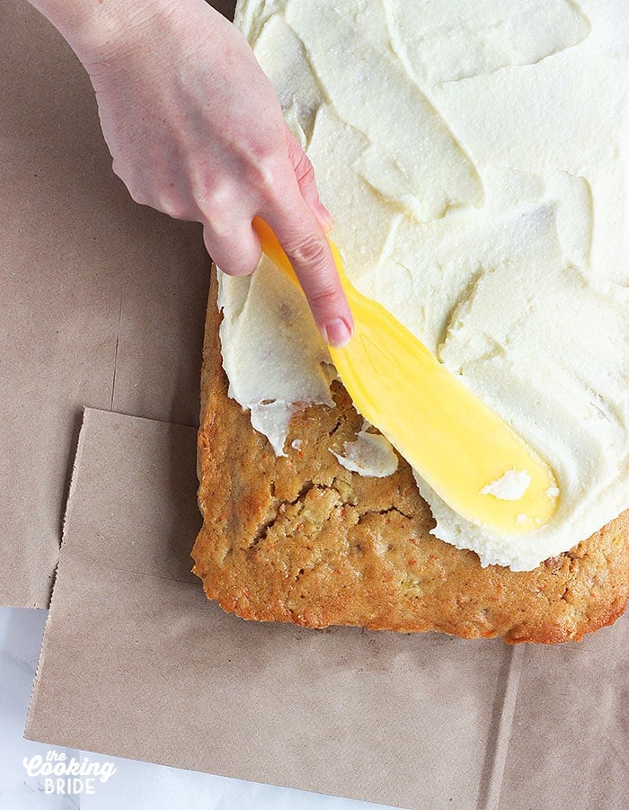 spreading cream cheese icing over a cake