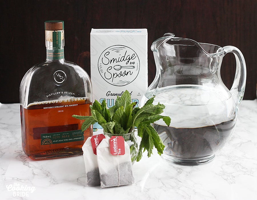 ingredients for a sweet tea mint julep including tea bags, sugar, bourbon and water
