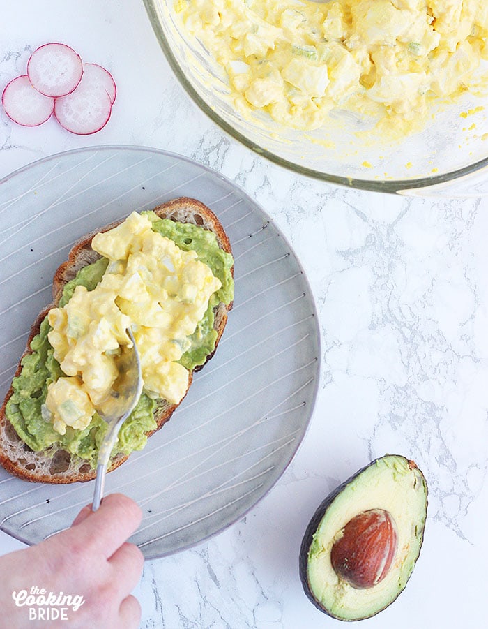 spreading egg salad on a slice of bread