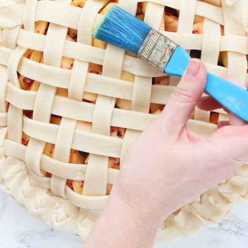 brushing egg wash on the lattice pie crust