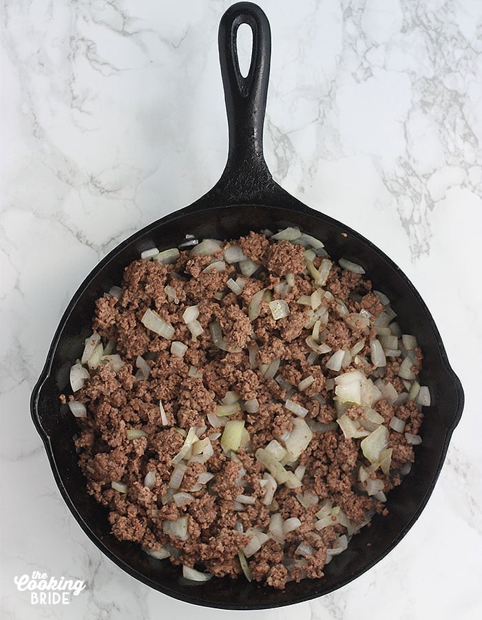 cast iron skillet with cooked hamburger and chopped onion