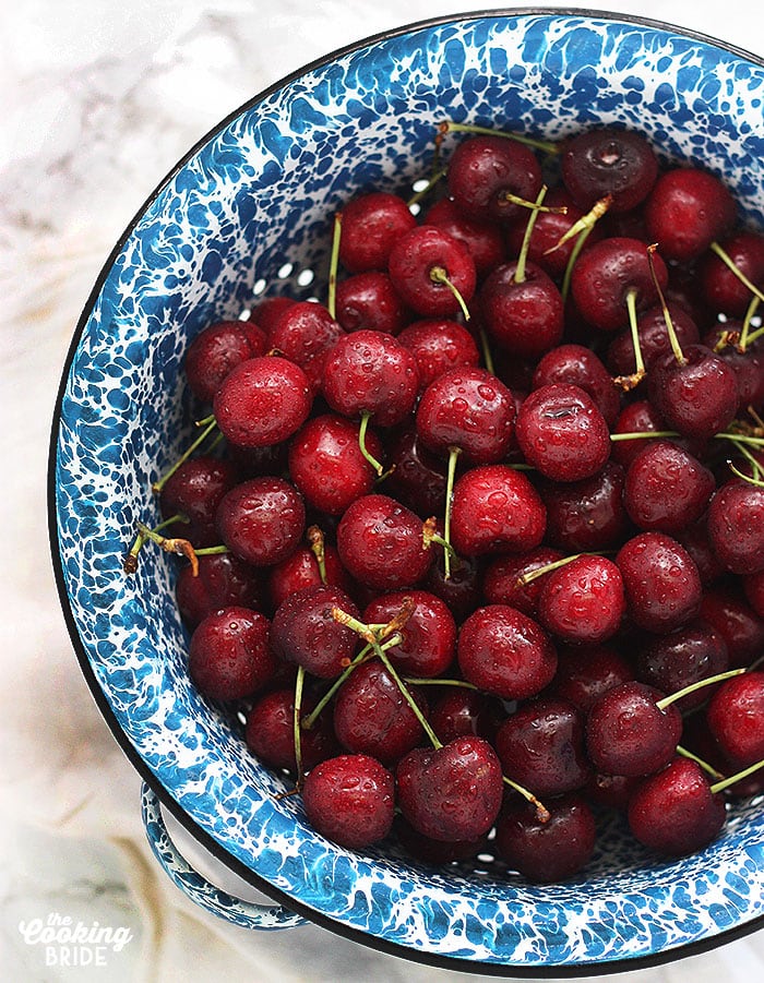 fresh red cherries in a blue and white speckled colander