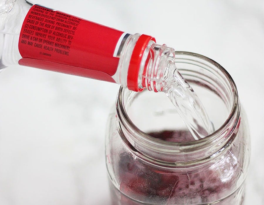 pouring vodka into a jar of cherries
