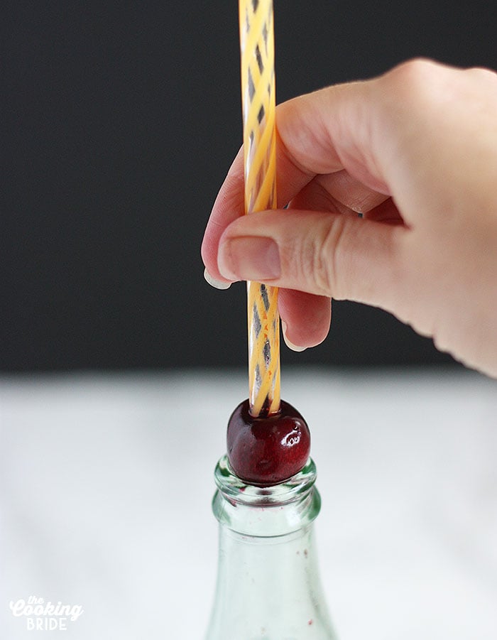 pitting a cherry using a straw and a glass bottle