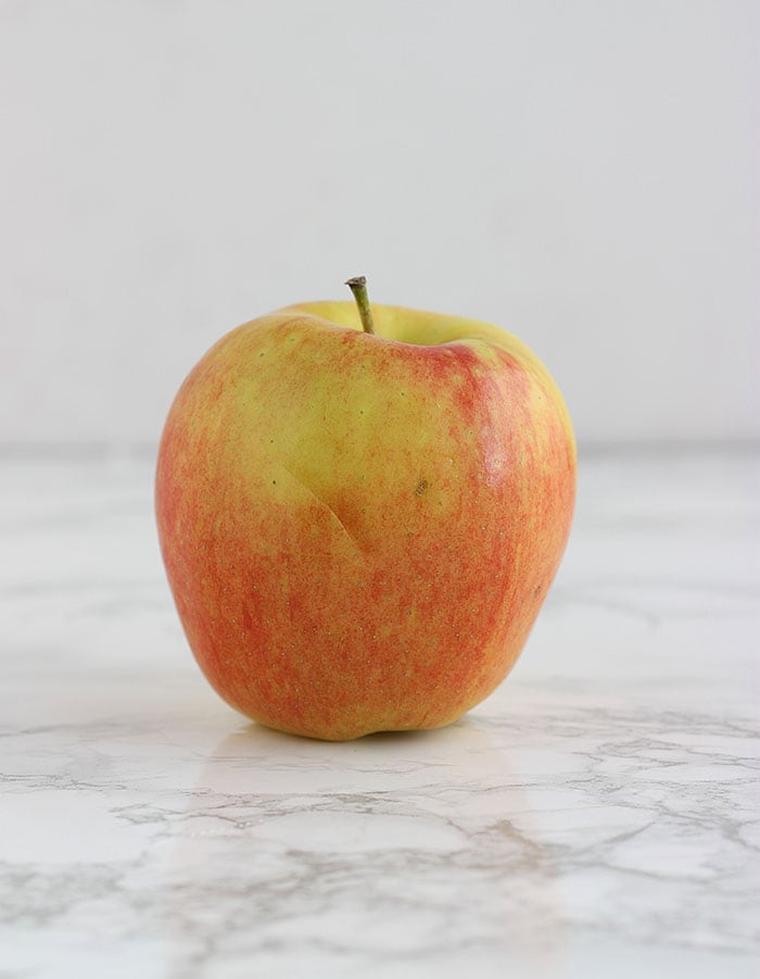 yellow and pink ambrosia apple on a white background
