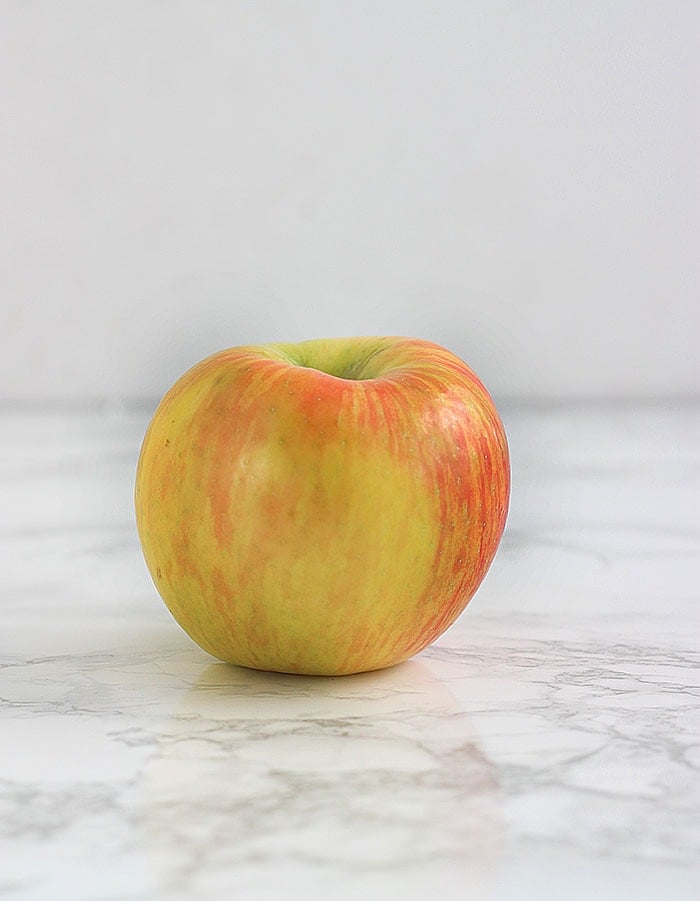 yellow and pink honeycrisp apple on a white background