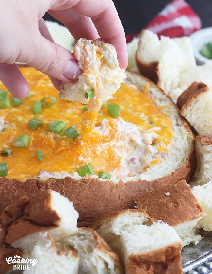 fingers dipping a piece of bread into the dip