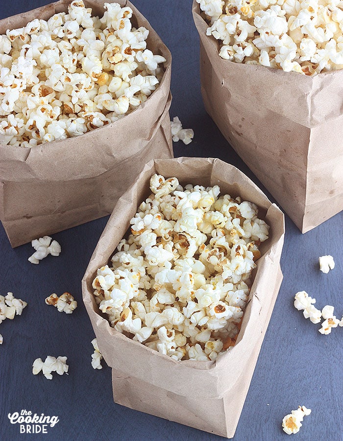 three paper sacks full of kettle corn on a blue background