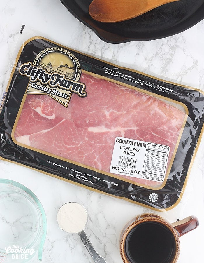 package of Clifty Farm country ham on a marble counter surrounded by coffee water and a skillet