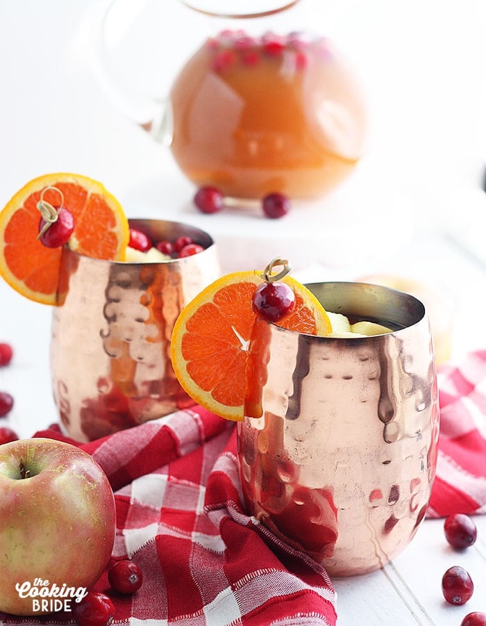 two copper mule cups of spiced apple cider against a red plaid napkin