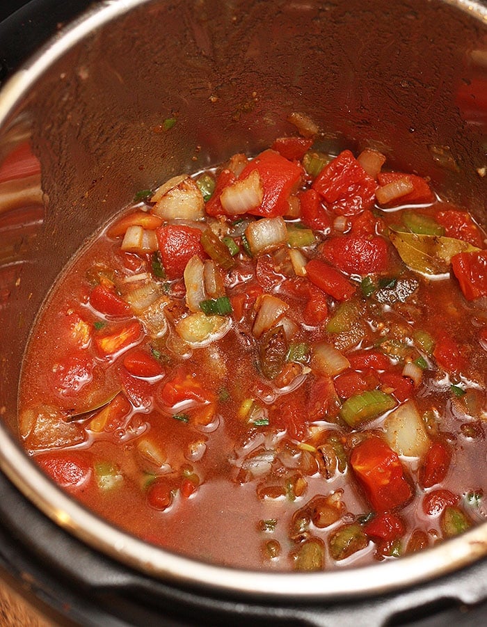 adding tomatoes and beef broth to the pot