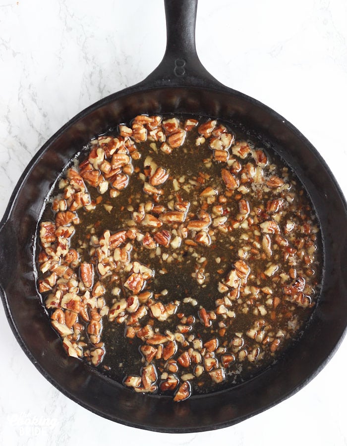 praline topping spread out over the bottom of a cast iron skillet
