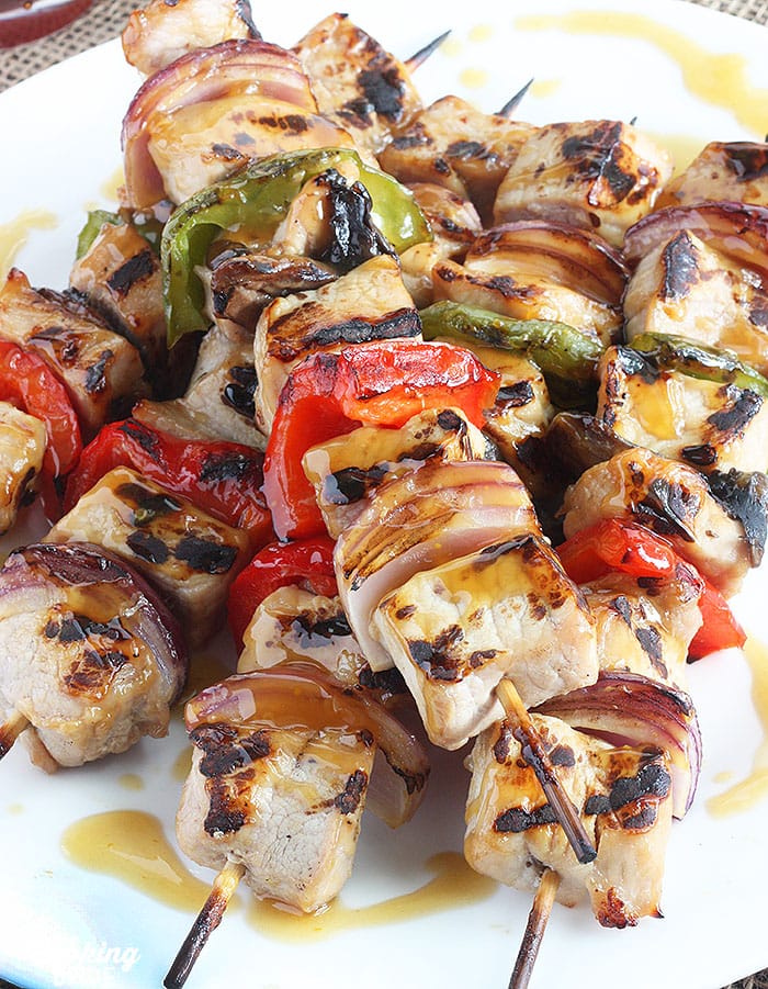 grilled pork skewers on a white platter drizzled with bourbon glaze