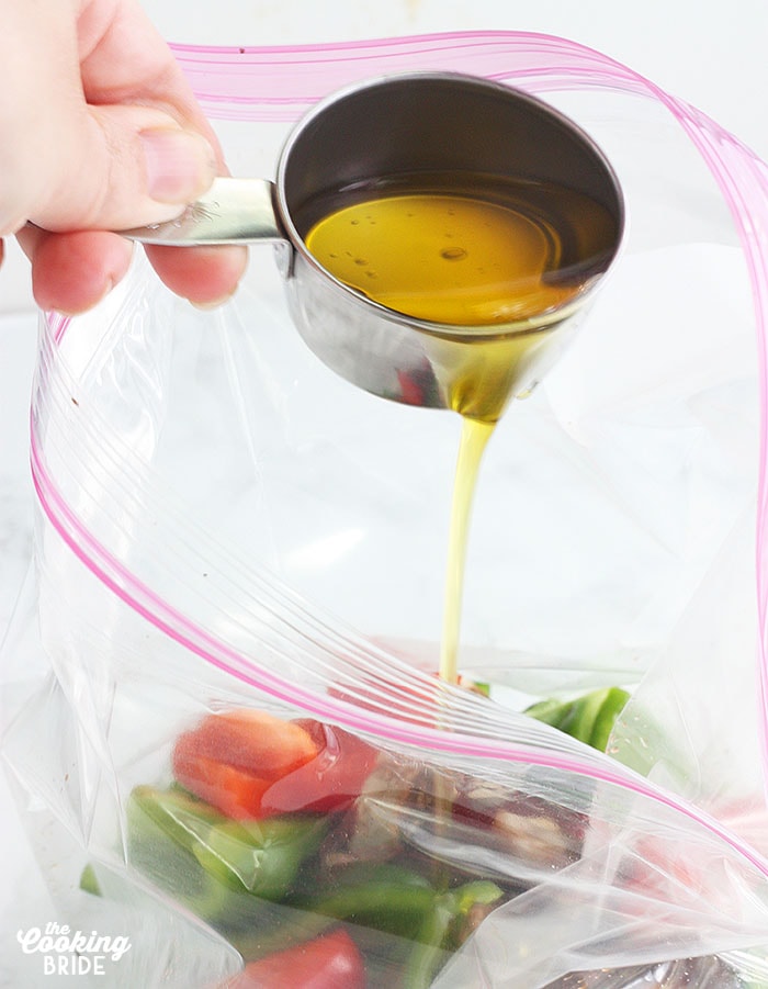pouring olive oil into a freezer bag full of vegetables