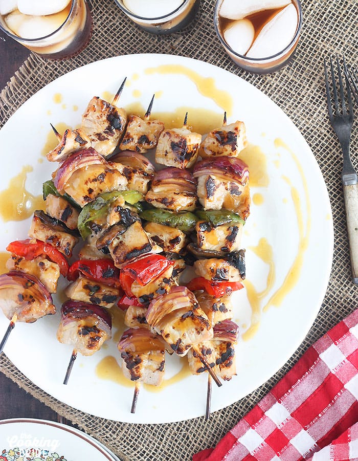 grilled pork skewers on a white platter drizzled with bourbon glaze
