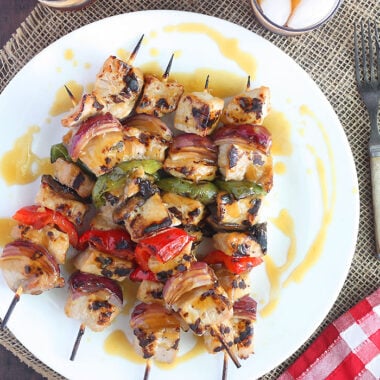 grilled pork skewers on a white platter drizzled with bourbon glaze