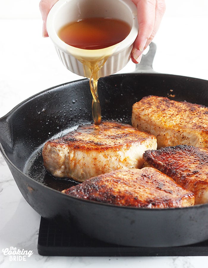pouring the maple glaze over the pork chops