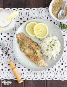 overhead shot of lemon pepper catfish fillet with rice an lemon slices on a gray plate