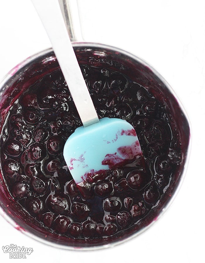 stirring blueberry filling in a metal pan